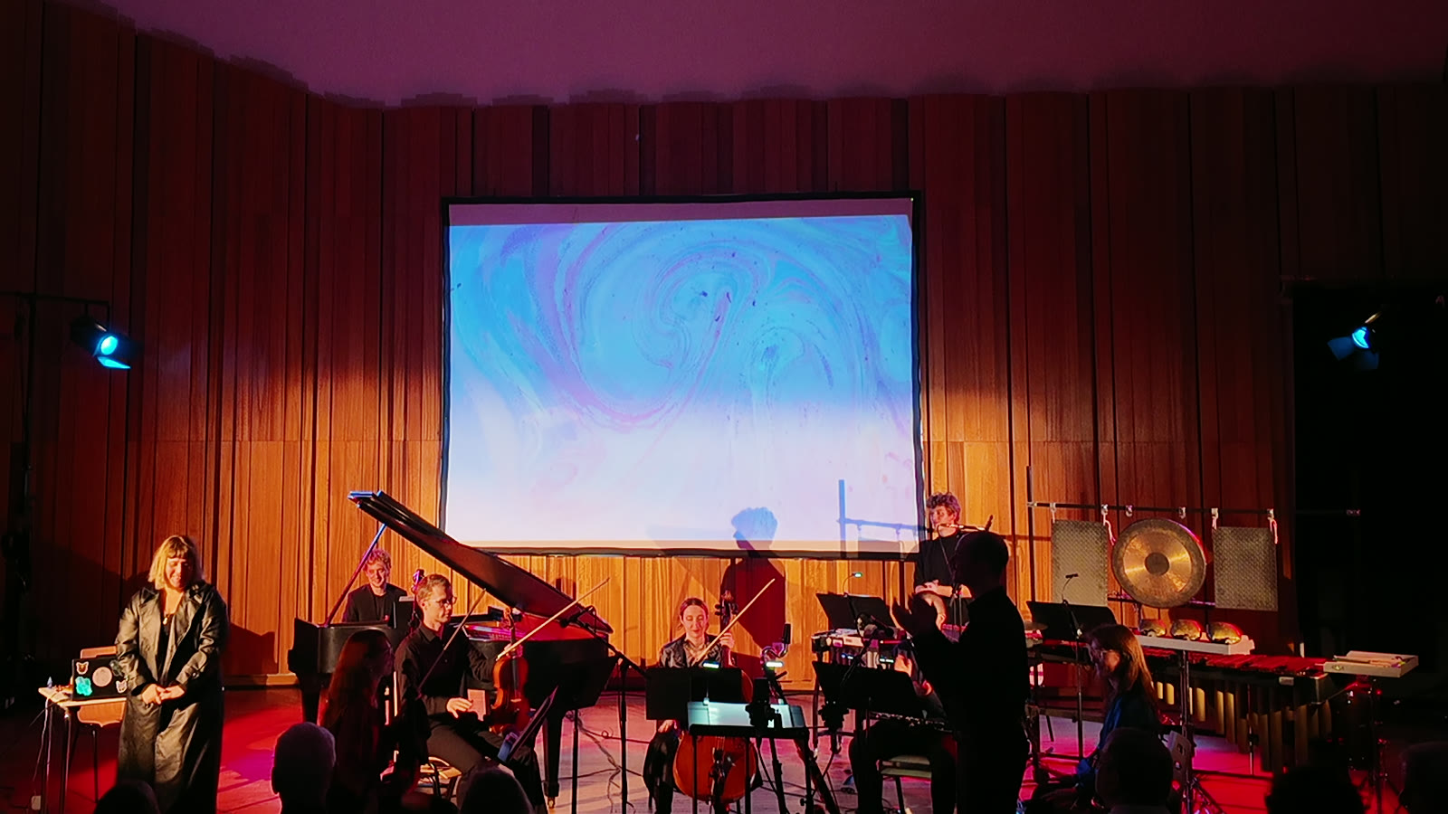 Eda Er and Ensemble éclat under stage light after the premiere, the final marbling still on the screen